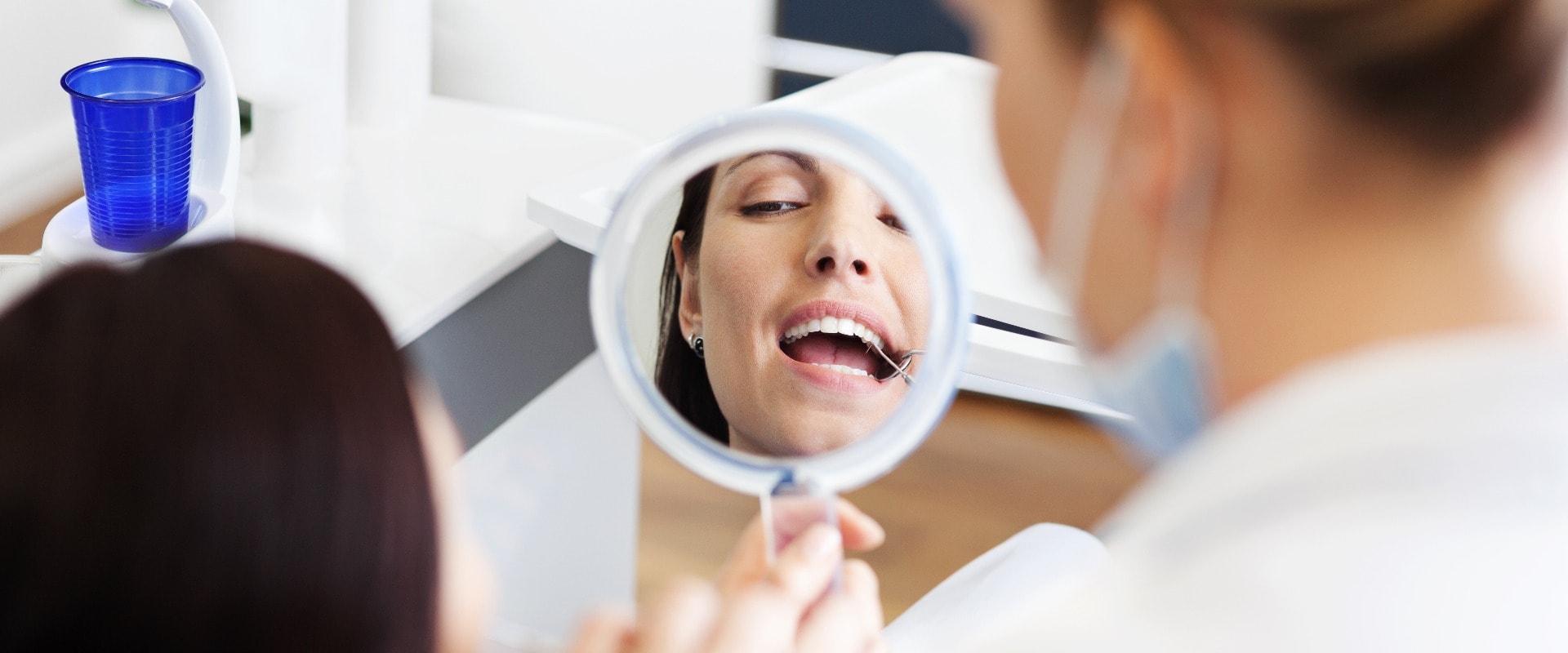 Frau beim Zahnarzt schaut in einen Spiegel