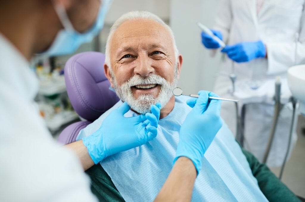Älterer Mann lächelt nach der Zahnersatz Behandlung