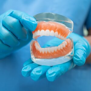 Zahnarzt hält Zahnprothese zur Untersuchung und Behandlung in der Zahnarztpraxis in Hamburg