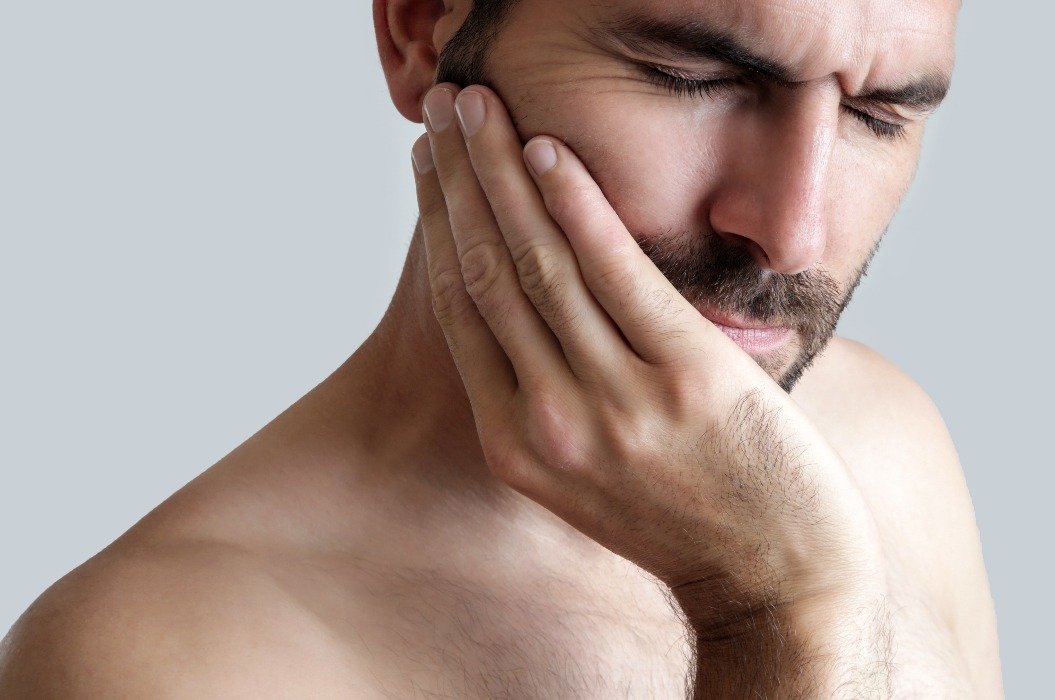 Studioaufnahme eines jungen Mannes mit Zahnschmerzen, Nahaufnahme