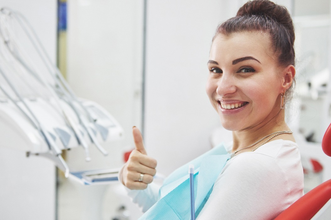Zufriedene Patientin zeigt ihr perfektes Lächeln nach der Behandlung in einer Zahnklinik