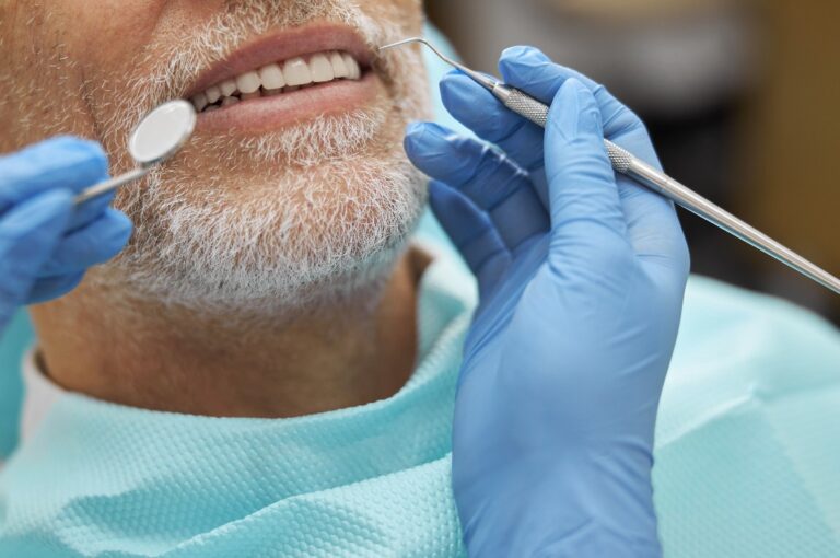 Ruhiger älterer Mann lächelt während einer zahnärztlichen Untersuchung