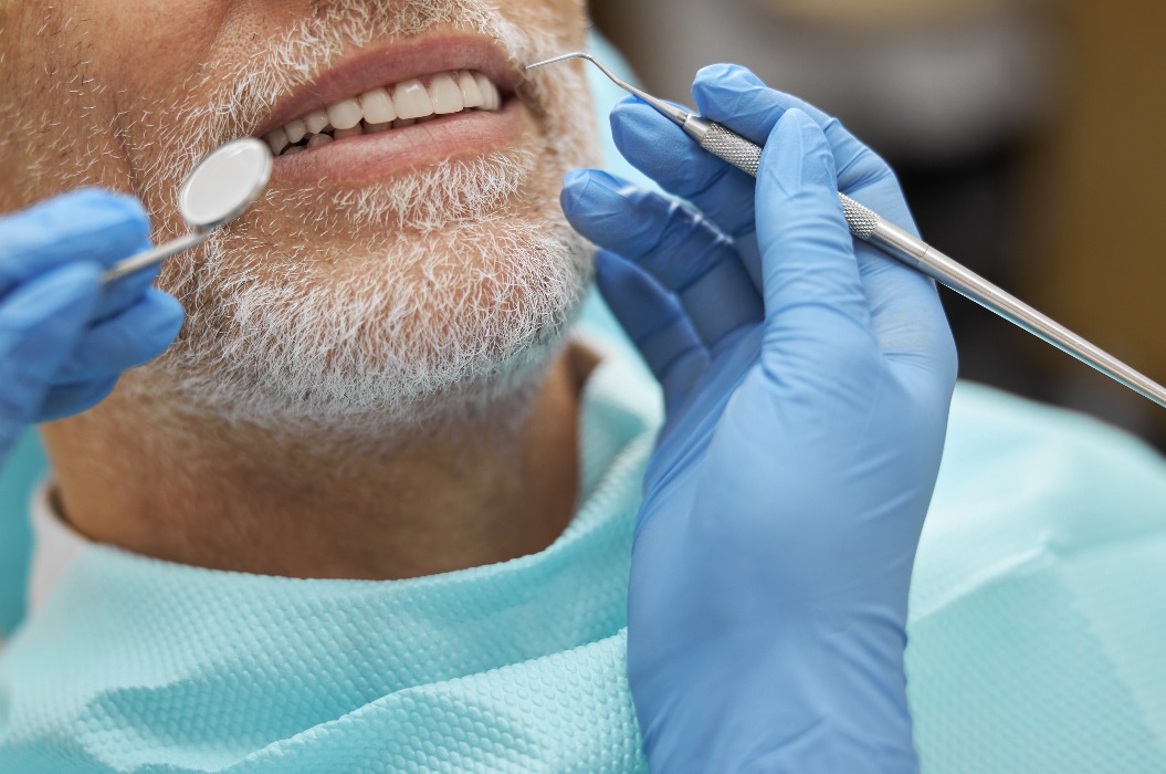 Ruhiger älterer Mann lächelt während einer zahnärztlichen Untersuchung