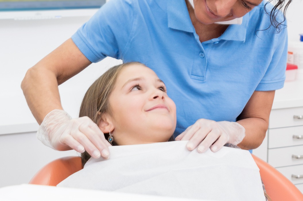 Zahnärztin beruhigt junge Patientin vor der Kontrolluntersuchung