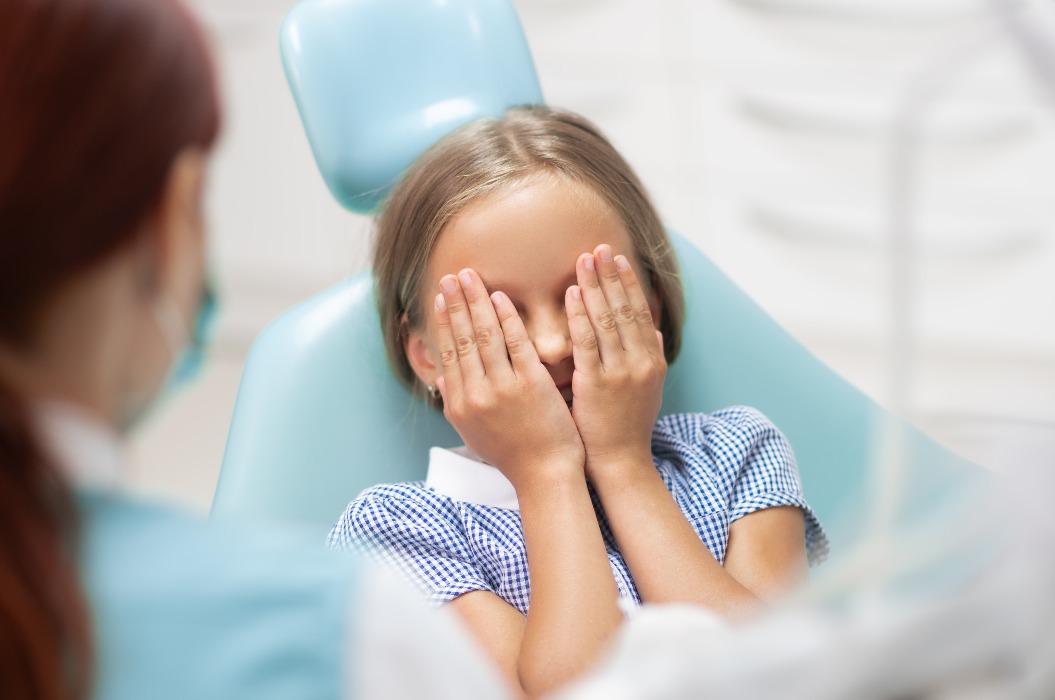 Kleines Mädchen schließt die Augen, weil sie Angst vor dem Zahnarzt hat.